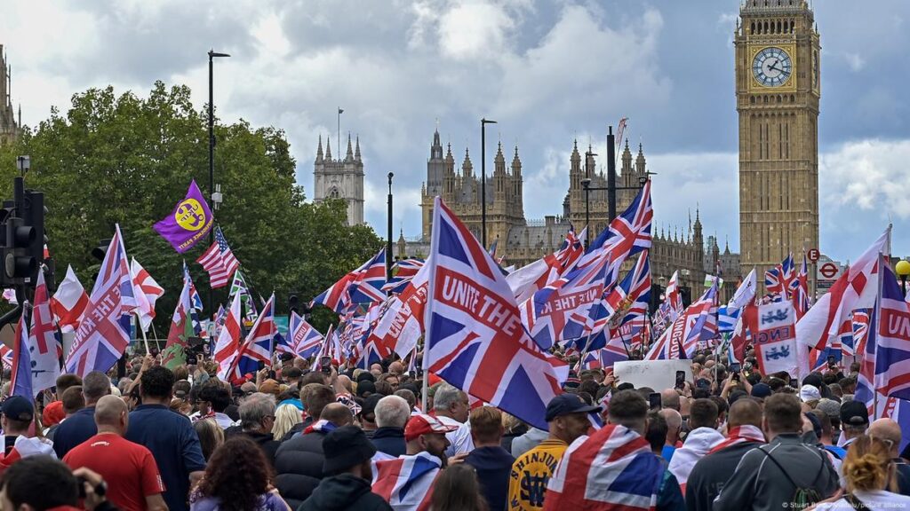 Protesters holding signs reading "Where Are Our Promises?" and "Cost of Living 